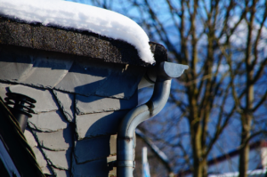 A close-up of a gutter downpipe covered with snow in a winter setting