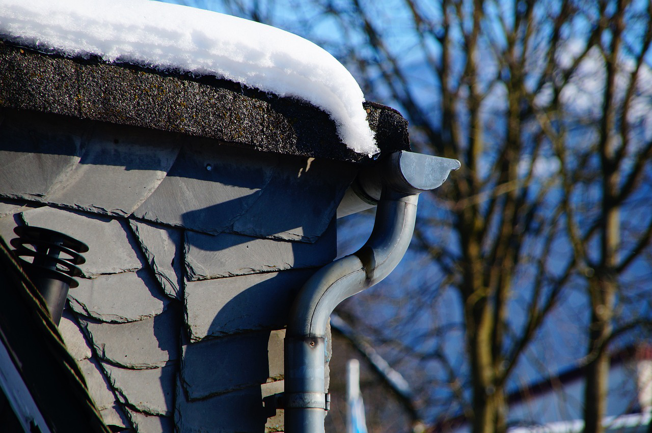 A close-up of a gutter downpipe covered with snow in a winter setting