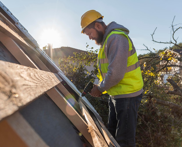 A man working on a roof with a drill, installing or repairing roofing materials.