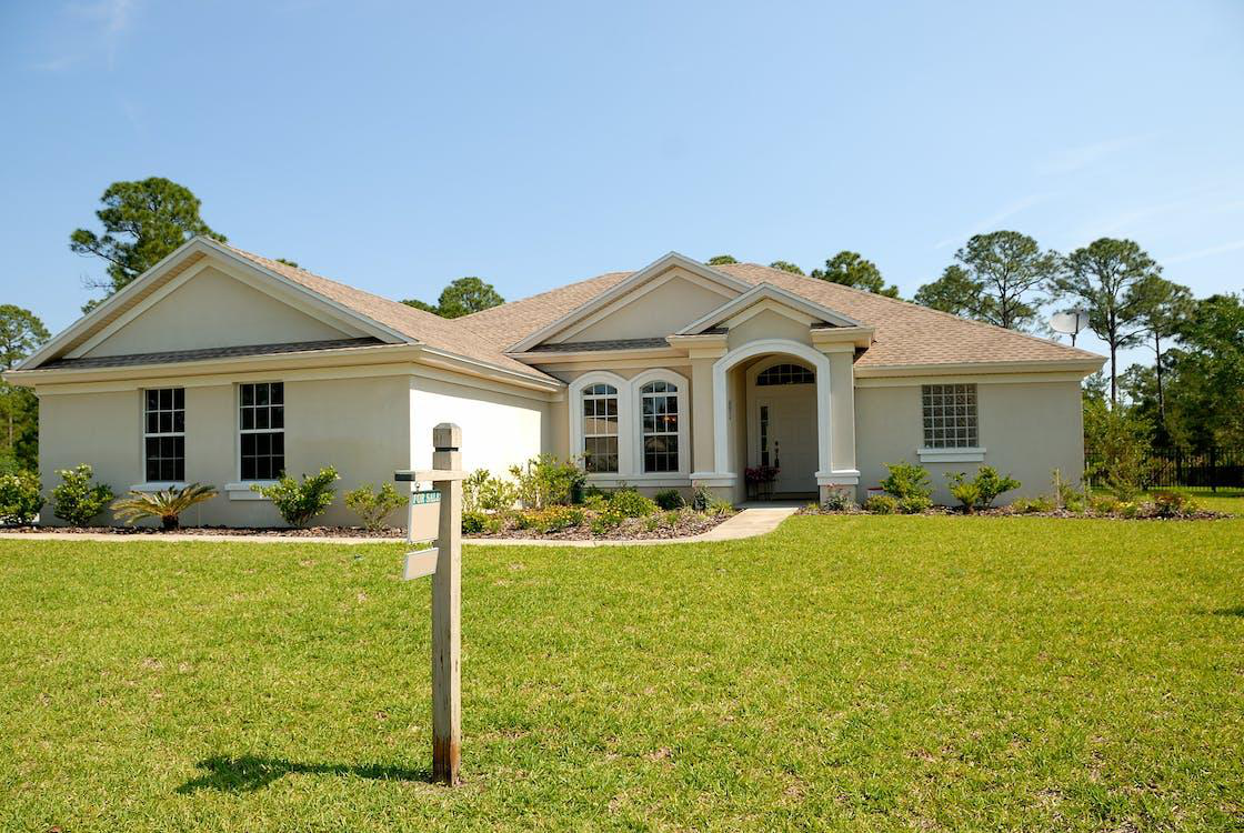 A white and brown concrete bungalow under a clear blue sky