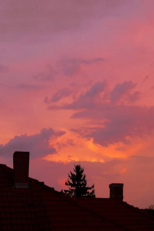 Sunset over rooftops with a visible chimney