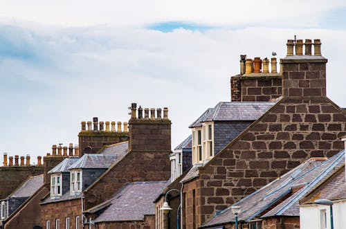 Row of houses with chimneys, illustrating the importance of chimney leak repair to protect roofs and walls from water intrusion.