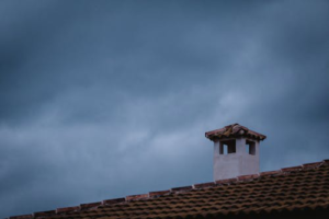 A chimney on a roof with visible signs of wear, emphasizing the need for timely chimney leak repair to avoid further damage.