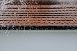 Water flowing off a roof during a rainstorm showcasing the importance of reliable roofing services.