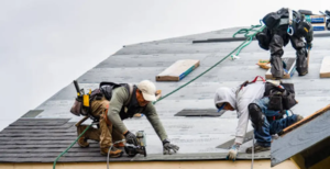 Roof contractors repair a roof using a drill and professional equipment