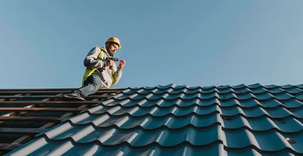 A roofing contractor using a drill to repair a residential roof